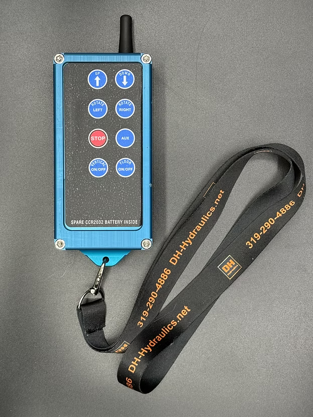 X8Pro wireless transmitter with blue anodized aluminum case, 8 control buttons, antenna, and carabiner clip attached to DH-Hydraulics branded lanyard.